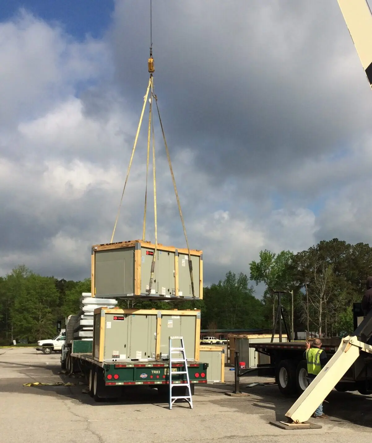 Crane lifting stacked modular containers onto flatbed truck