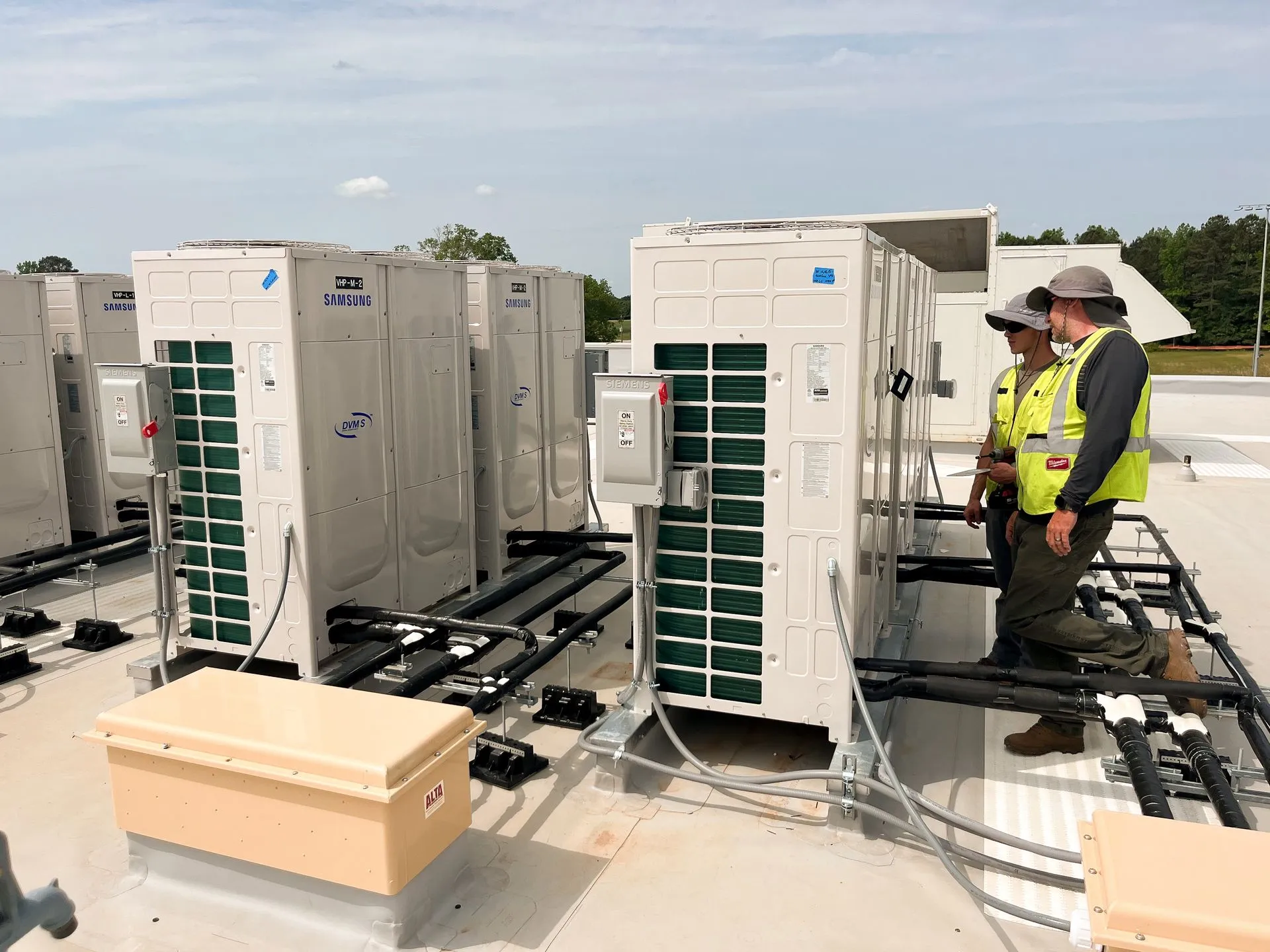 Technicians inspecting commercial rooftop HVAC units